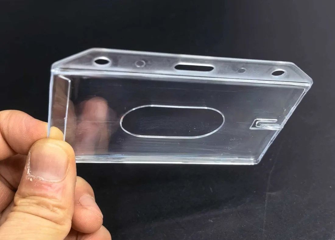 Rigid ID card holder held in hand, showing depth and thumb slot